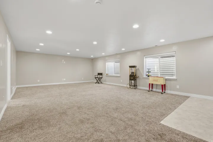 Expansive room with neutral carpeting, recessed lighting, multiple windows, and light-toned walls *without virtual staging*