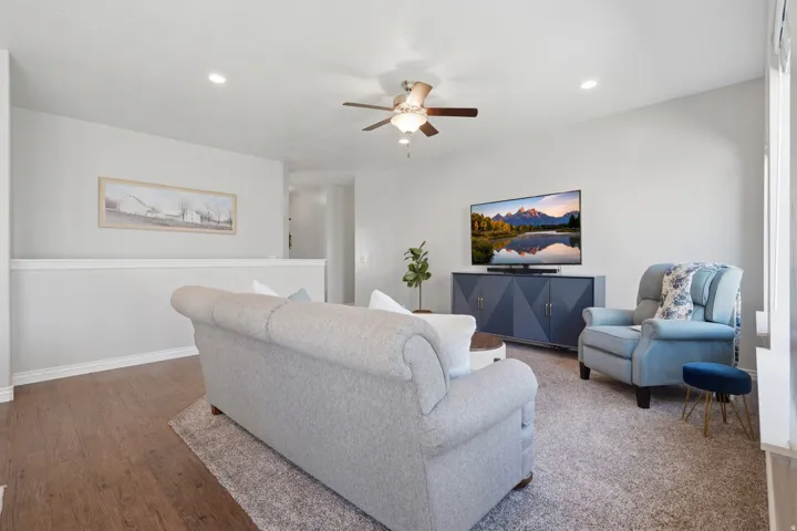Recessed lighting, wood-finish flooring, ceiling fan, carpeted area, and a half-wall partition
