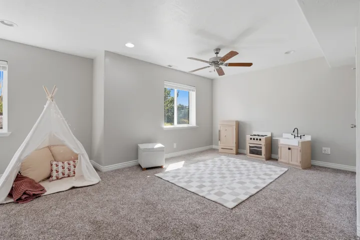 Plush carpet flooring, multiple windows, recessed lighting, and a ceiling fan with wood-finish blades