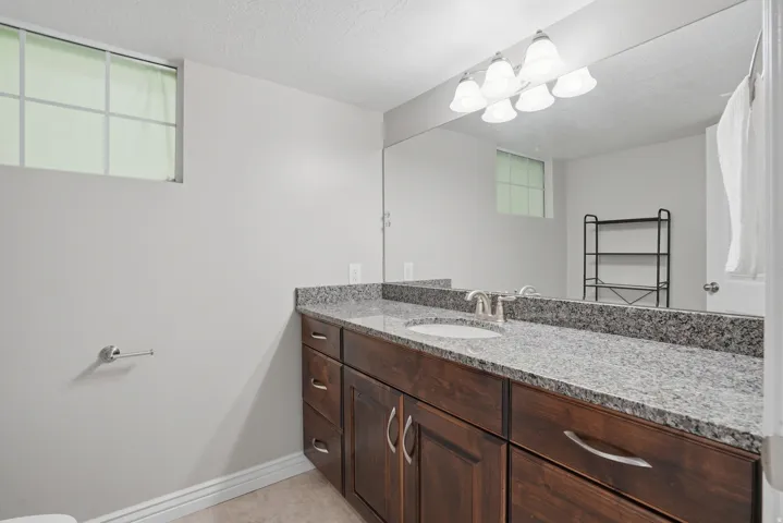 Dark wood-finish vanity with a light granite-patterned countertop, undermount sink, and brushed nickel faucet