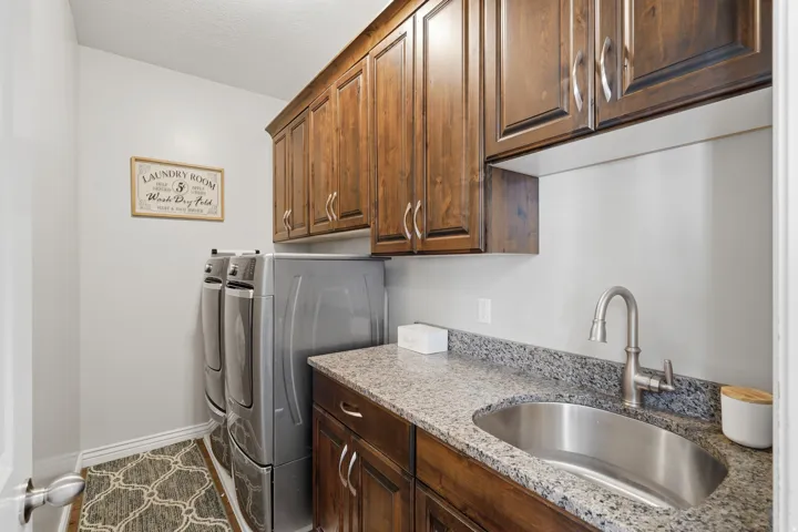 Built-in wood cabinetry, integrated stainless steel sink, granite-style countertop, and modern faucet