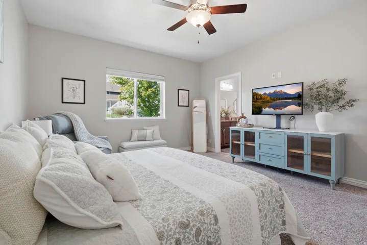 Carpeted bedroom with a ceiling fan, a window, and a white door frame