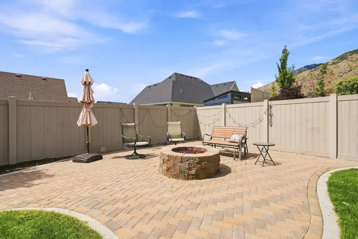 Paver patio featuring a built-in stone-clad fire pit, surrounded by a privacy fence