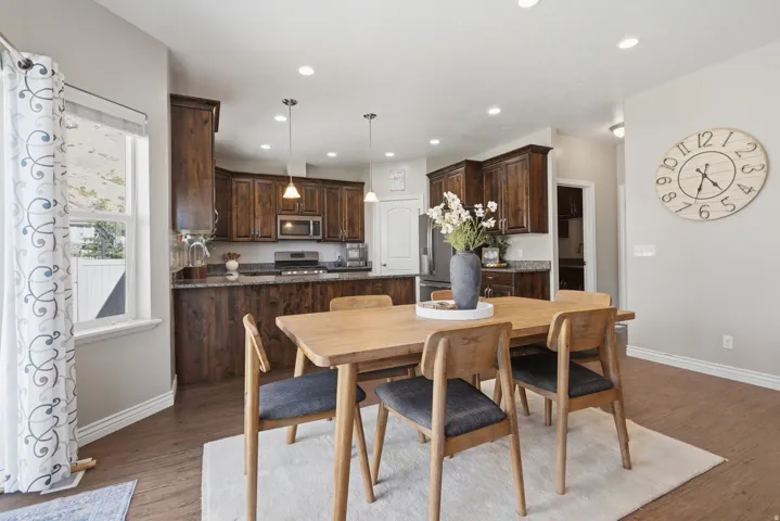 Open-concept kitchen featuring wood-finish flooring, dark wood cabinetry, stainless steel appliances, and recessed lighting