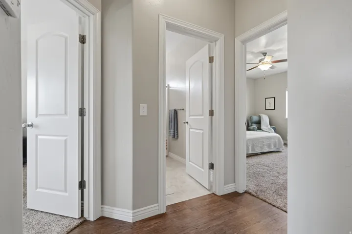 Hallway featuring wood-finish flooring, white panel doors, and neutral wall paint