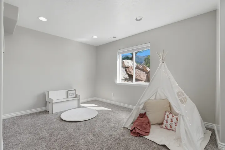Recessed lighting, large window, mountain scenery, gray carpeting, and light gray wall paint