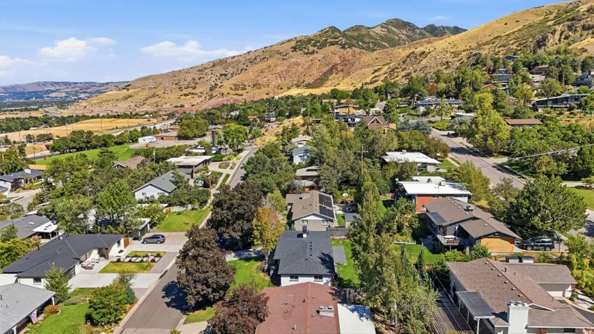 Residential neighborhood with mature trees, established landscaping, and mountain backdrop