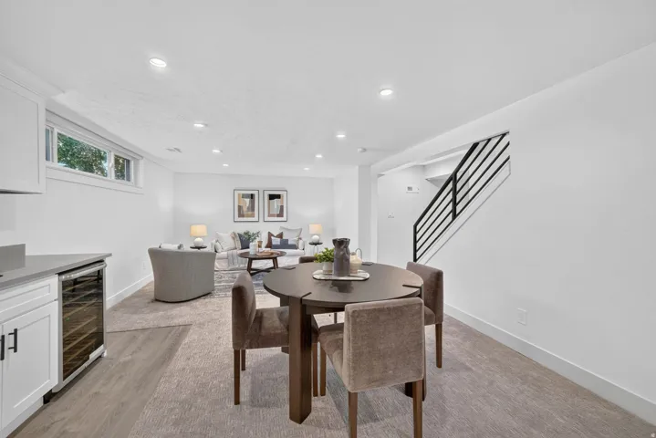 Open concept recreation room with recessed lighting, wood-finish flooring, built-in beverage cooler, and a contemporary metal staircase railing