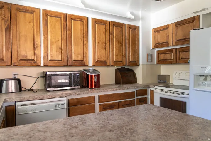 Wood cabinetry, integrated dishwasher, and white electric range