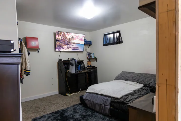 Wall-mounted shelving, built-in desk area, recessed lighting, and a single window with black window treatments