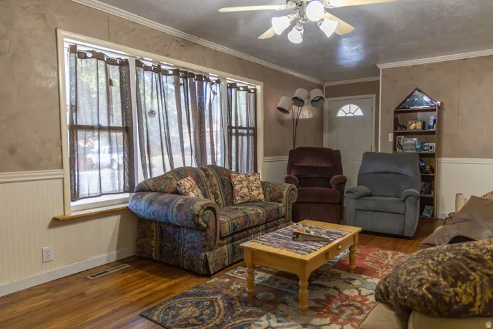 Wood-finish flooring, white beadboard wainscoting, and a multi-pane window