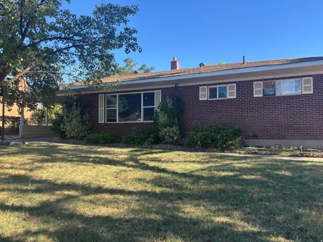 Brick exterior with a large front window, white shutters, and a chimney