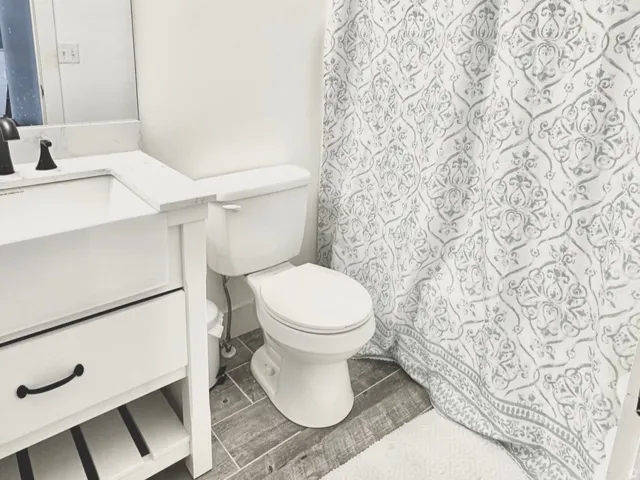 End of hallway bathroom on 3rd floor. White vanity with black hardware, integrated rectangular sink, and white quartz countertop