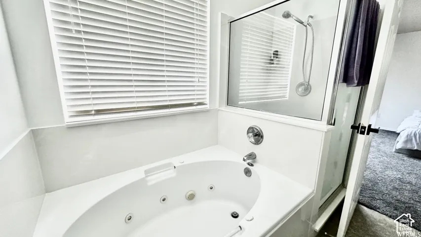 Master bathroom - Spa-inspired primary bath featuring a sunken whirlpool tub with integrated jets, dual control fixtures, and a frameless glass shower enclosure