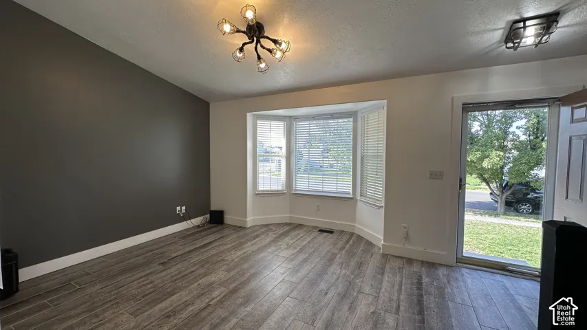 Featuring tile flooring, a prominent bay window that brings in abundant natural light, a modern multi-bulb ceiling fixture, a contrasting accent wall, and a storm-door entry.