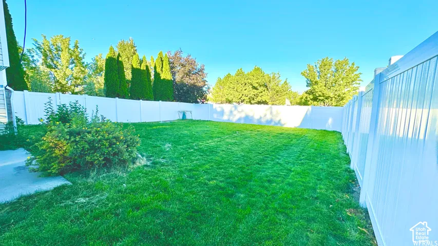 Expansive grass lawn bordered by a white vinyl fence, offering plenty of space to make the backyard your own