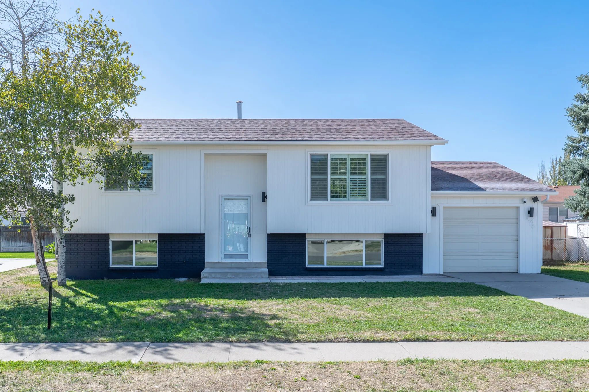 Split-level architecture featuring white siding and a dark brick foundation