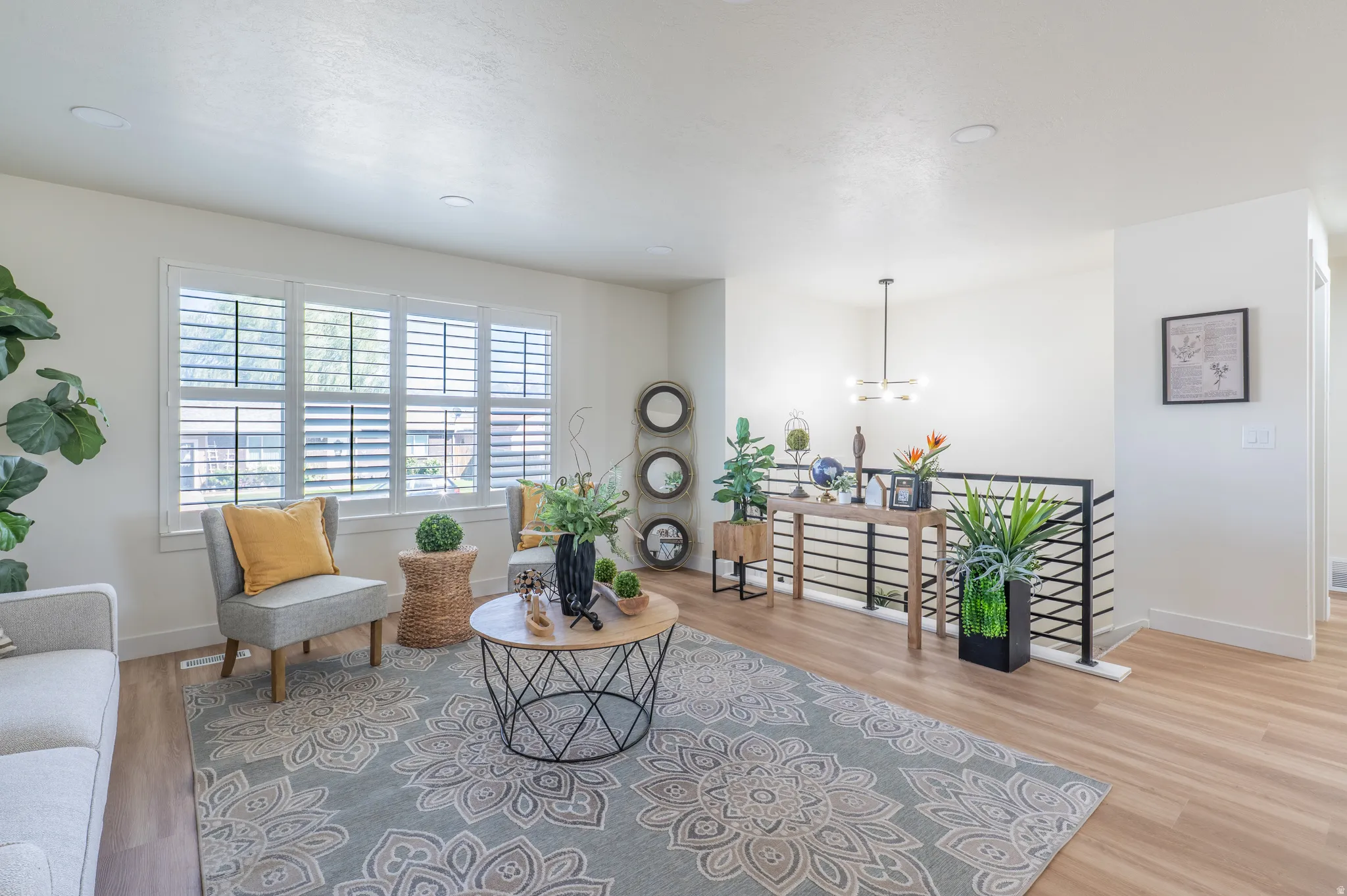 Expansive living area featuring light wood-finish flooring, recessed lighting, and large windows with plantation shutters