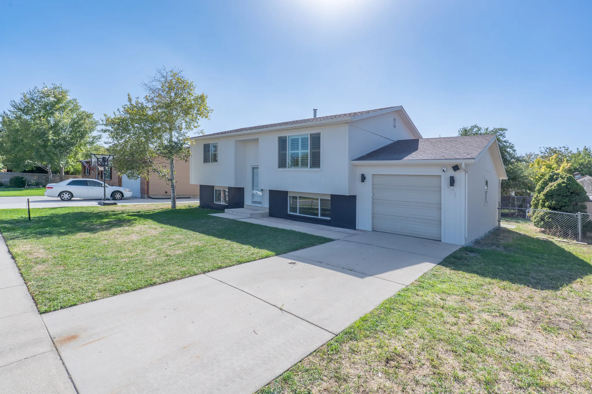 Split-level residence featuring a two-tone exterior, attached garage, concrete driveway, and front lawn