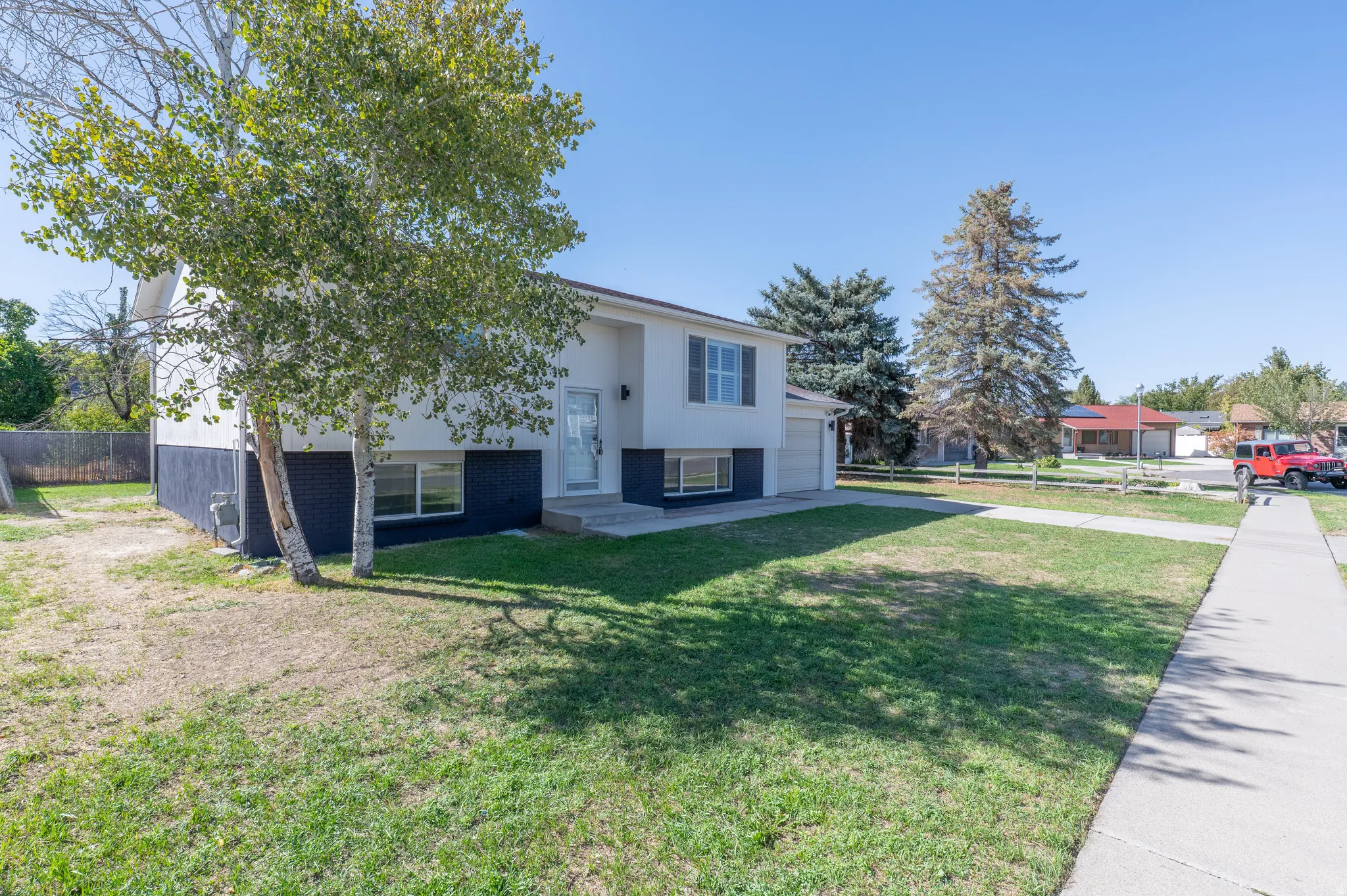 Split-level architecture with a two-tone exterior, featuring a paved sidewalk and a front lawn