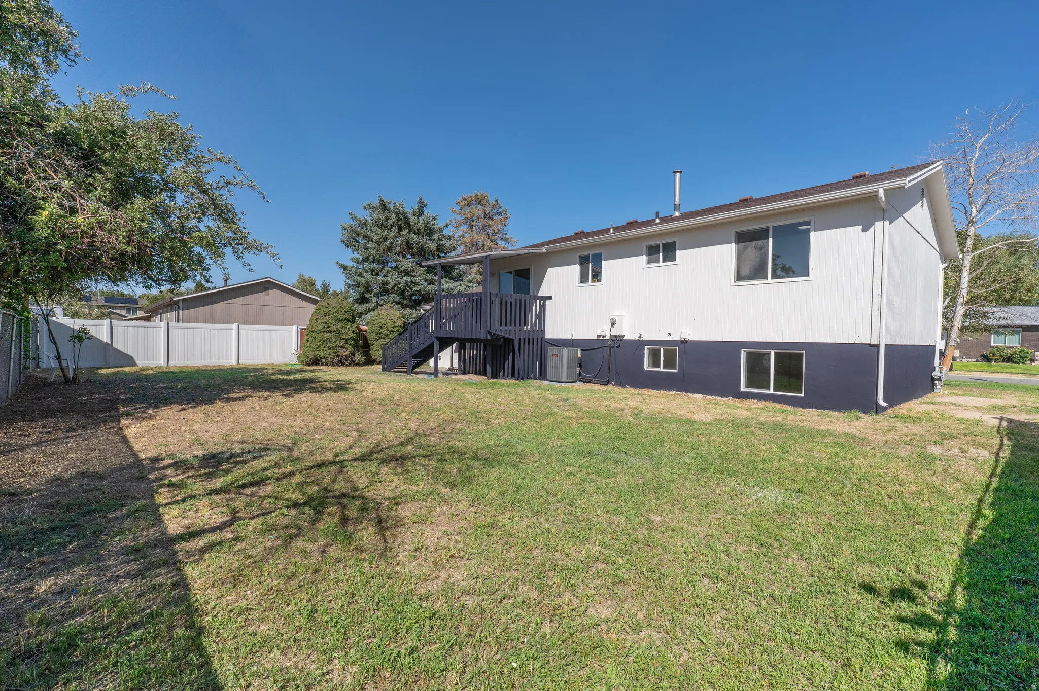 Expansive lawn area with a white privacy fence and mature perimeter trees