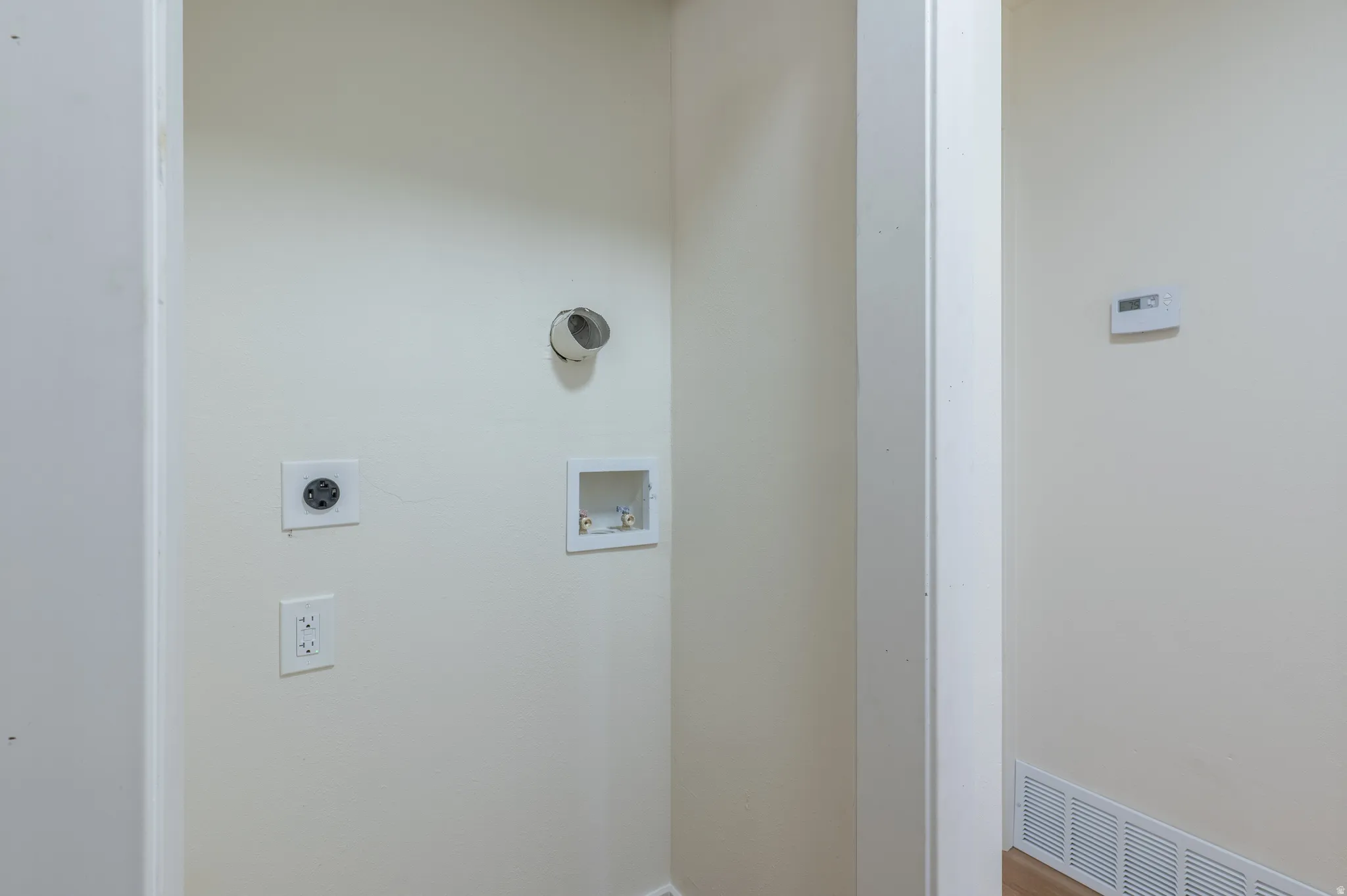 Dedicated laundry area with utility hookups and wall-mounted thermostat
