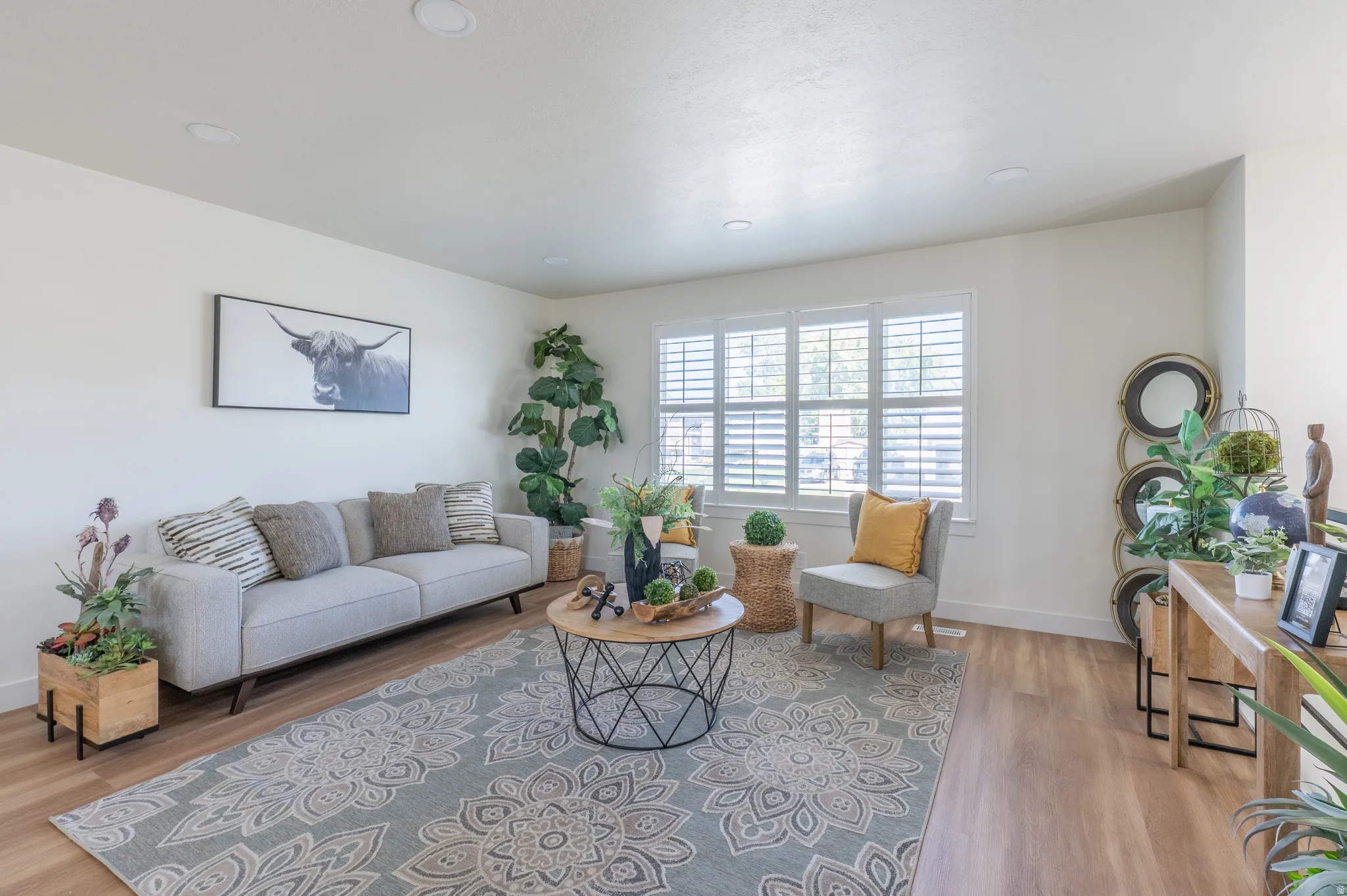 Recessed ceiling lighting, wood-finish flooring, white wall paint, window with white louvered shutters, and white trim
