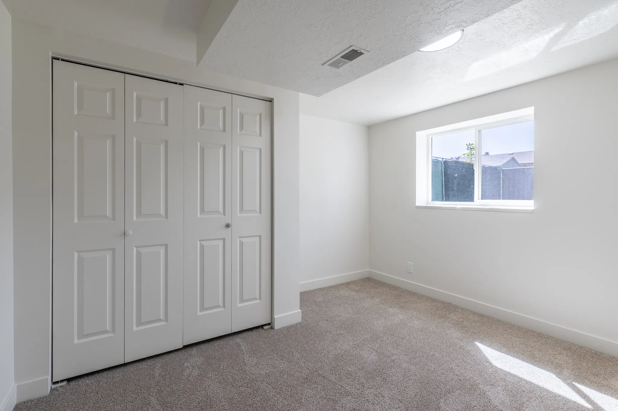 Neutral-toned carpeting, white walls, and a window providing natural light