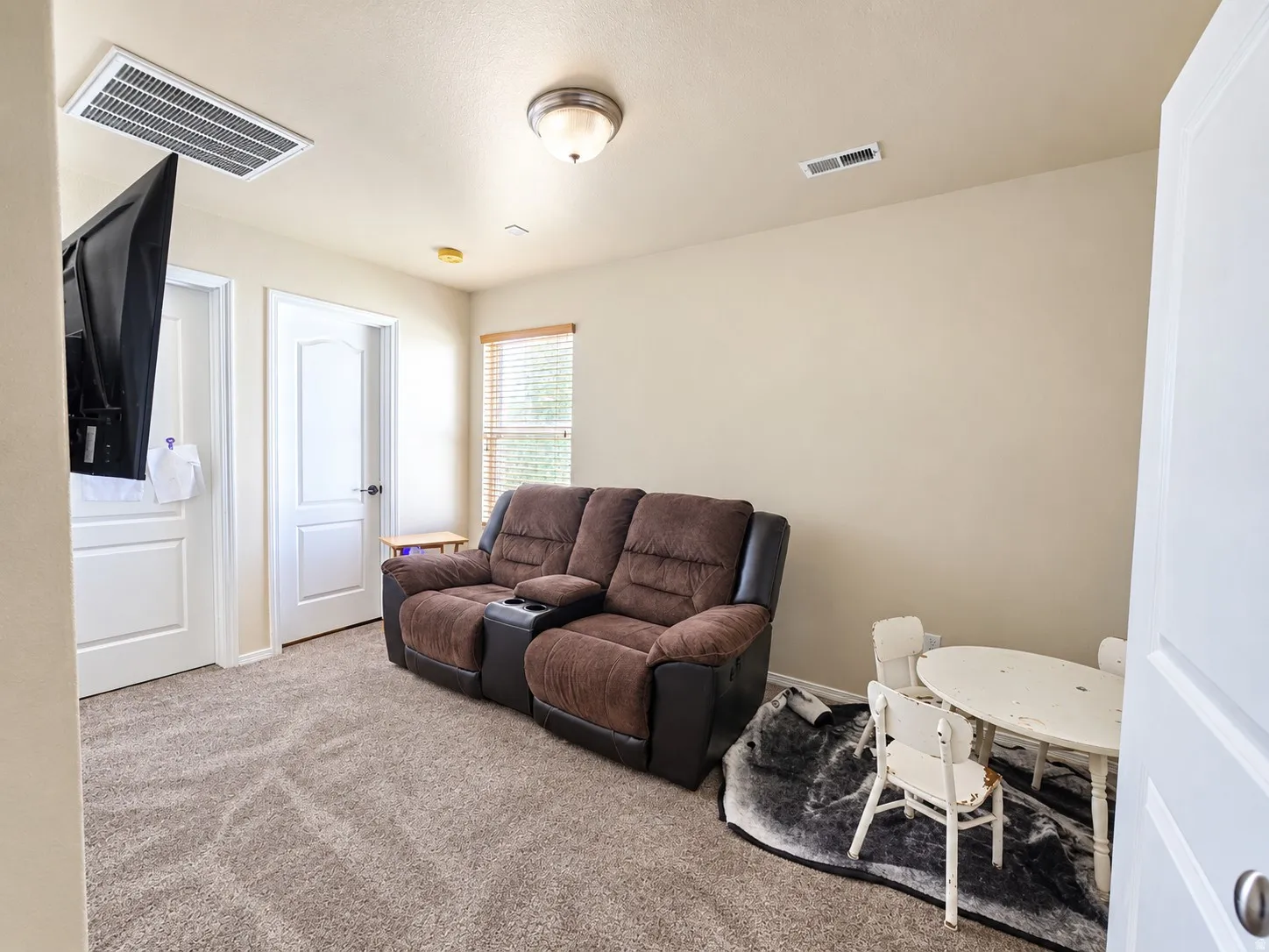 Carpeted interior with light-toned walls, a single window with blinds, and white interior doors