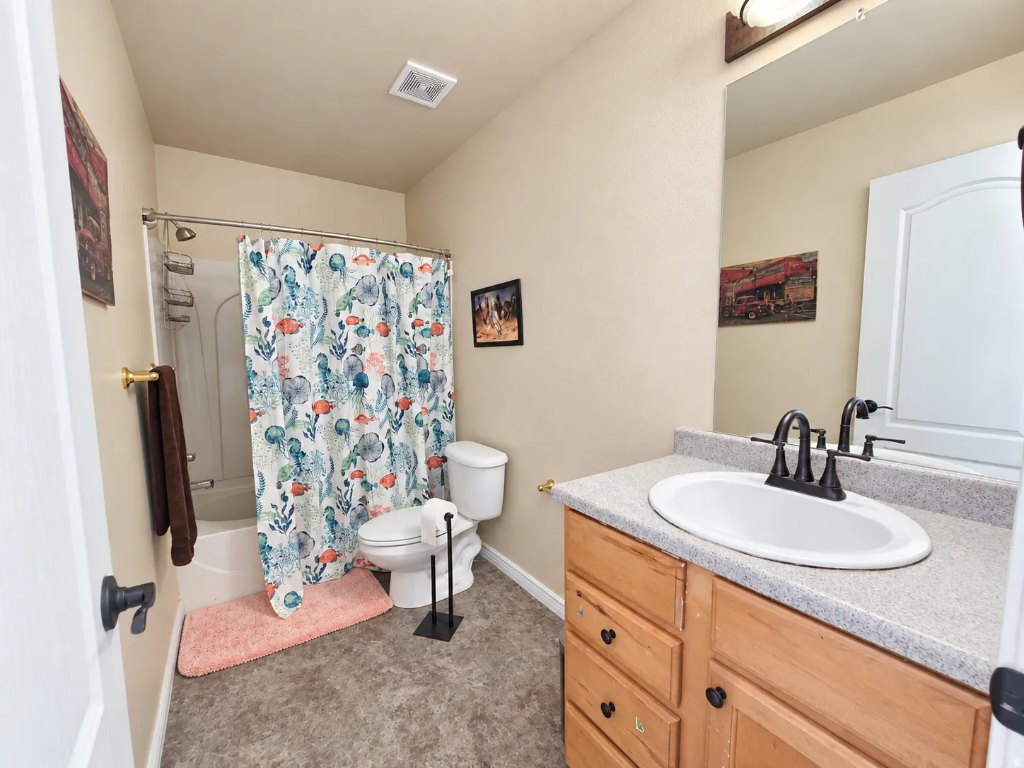 Single vanity with integrated sink, wood-finish cabinetry, and dark bronze fixtures