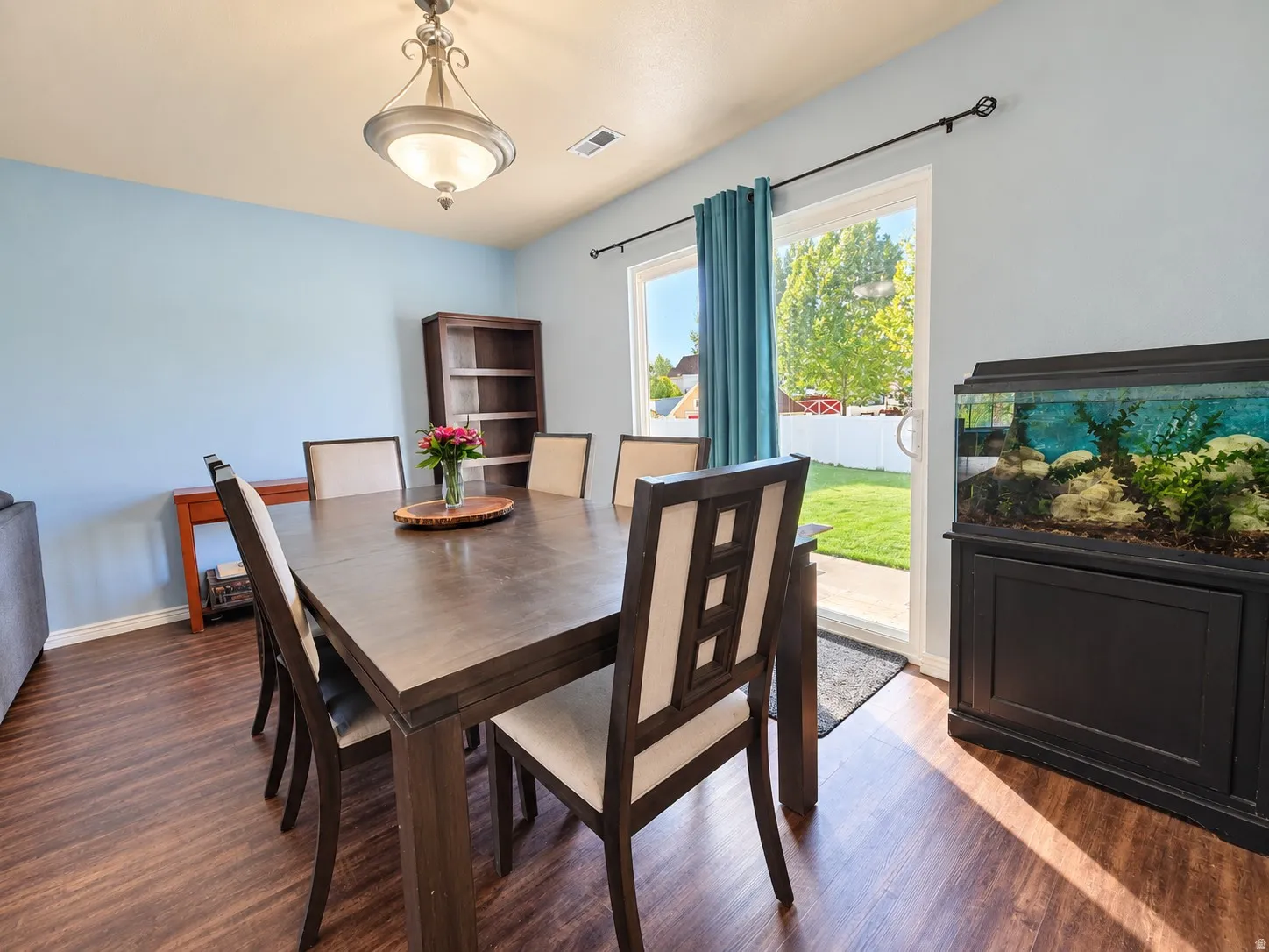 Wood-finish flooring, overhead light fixture, sliding glass door, and a fenced backyard