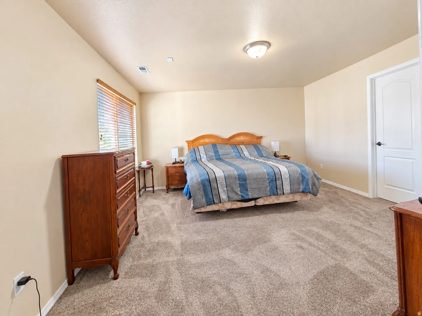 Carpeted flooring throughout, neutral wall paint, overhead flush-mount lighting, and window with blinds