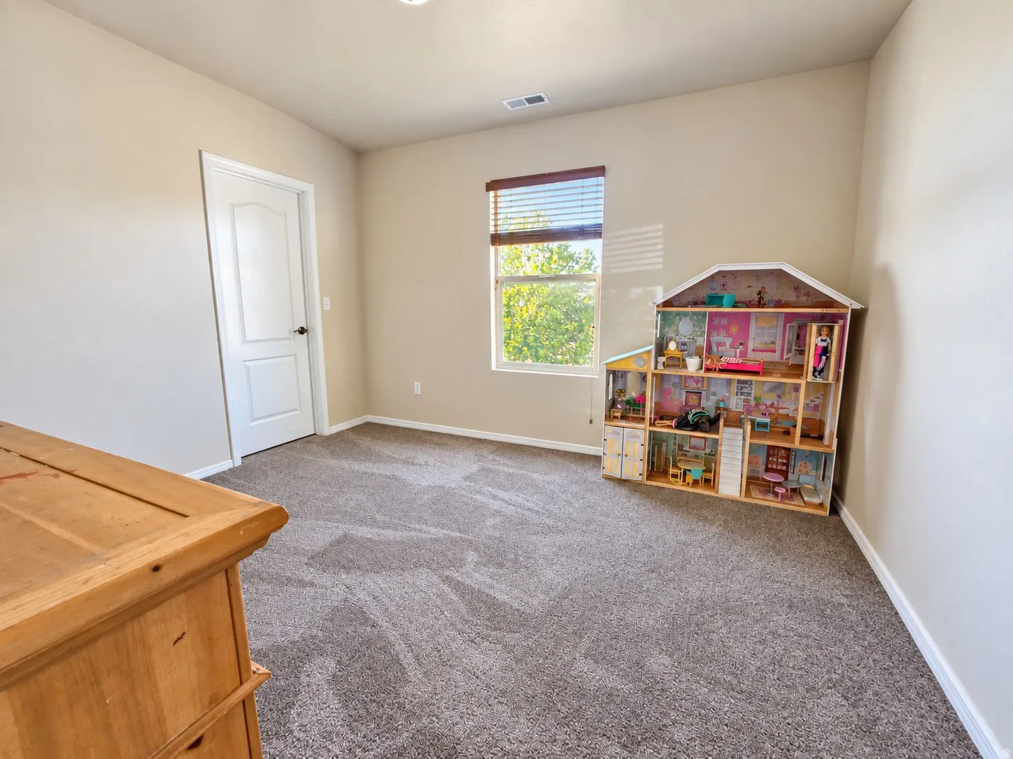 Wall-to-wall carpeting with a neutral tone, light-colored walls, and a window with blinds