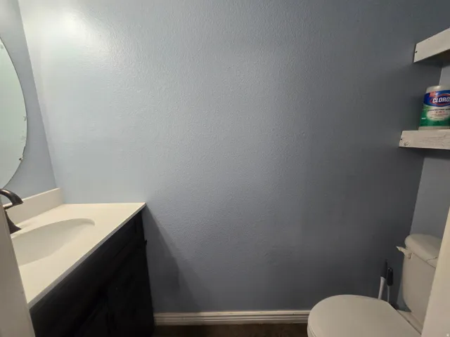 Vanity with integrated sink, dark wood-finish cabinetry, and brushed bronze faucet
