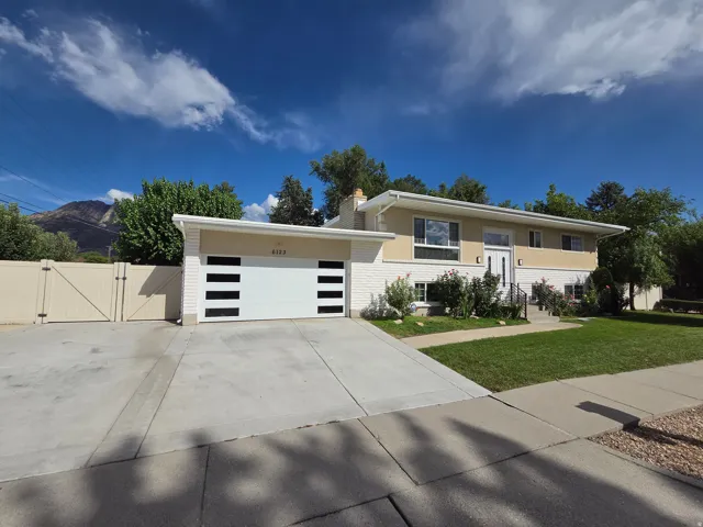 Split-level property featuring a modern garage door, white brick, and a beige exterior