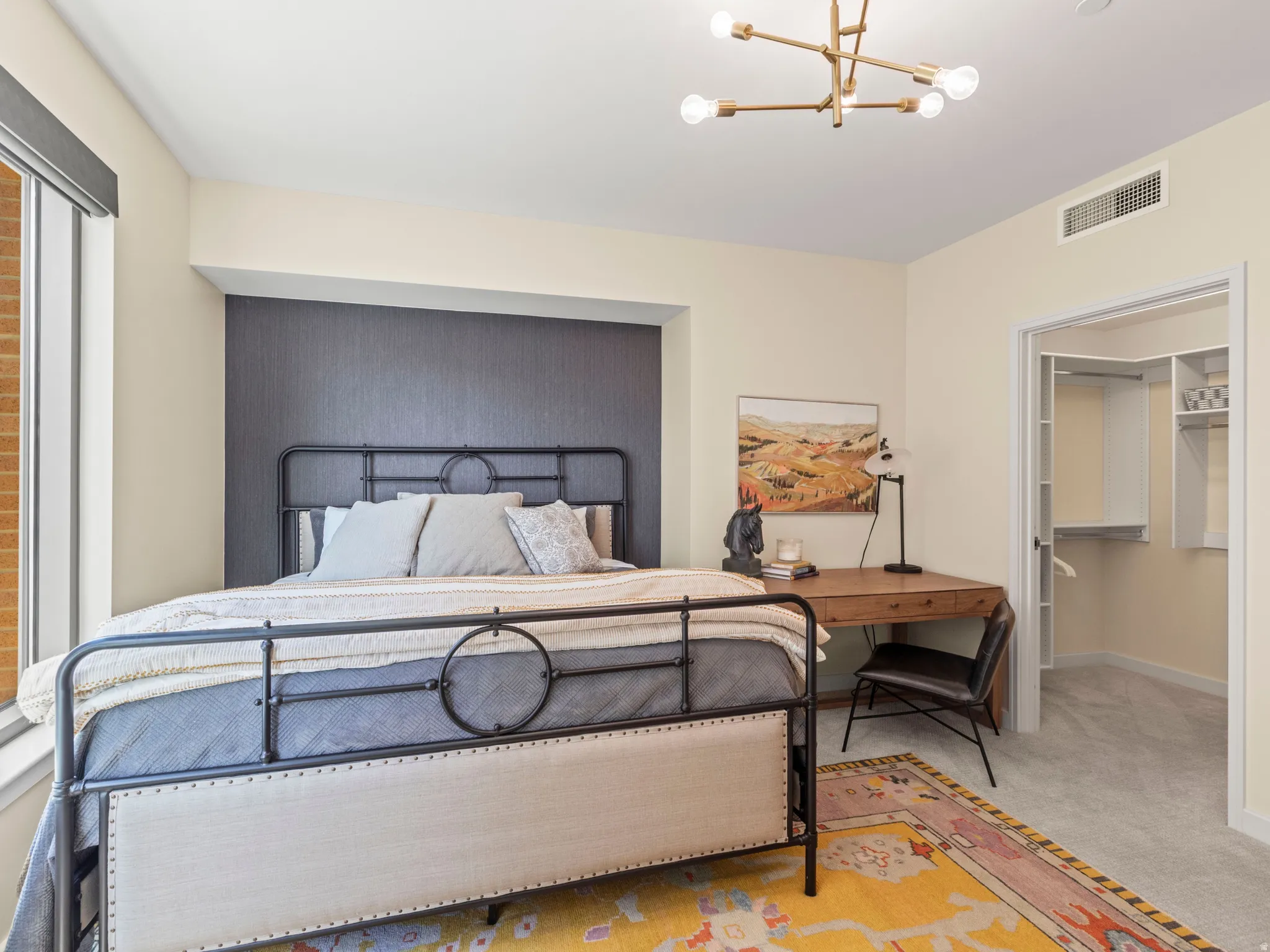 Large window, geometric ceiling light fixture, accent wall, built-in closet organization, carpeted flooring