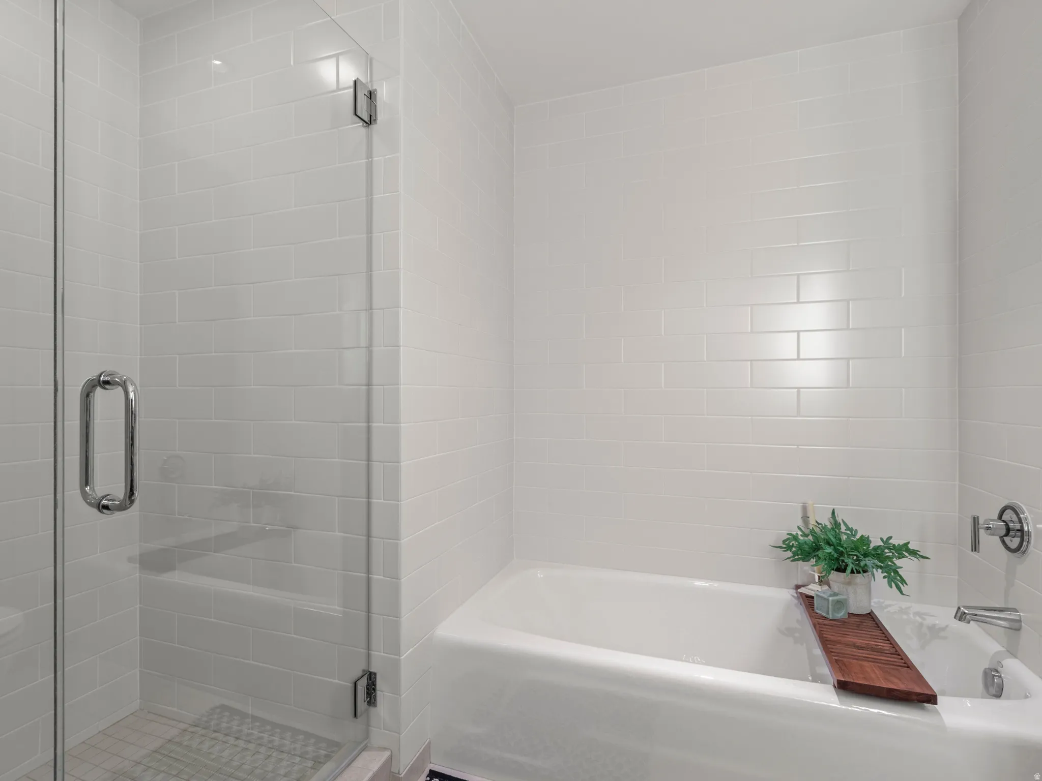 White subway tile surround, glass-enclosed shower, built-in bathtub, and chrome fixtures