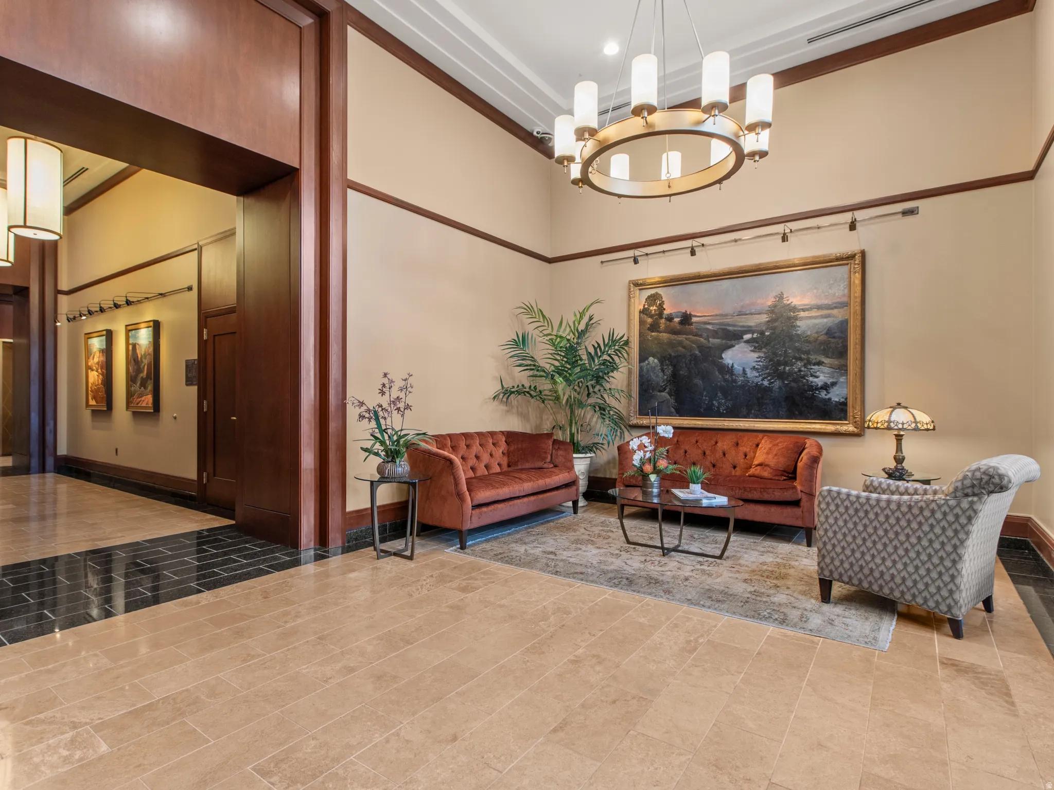 Expansive common area featuring wood paneling, recessed lighting, a large circular chandelier, and a combination of light and dark tile flooring