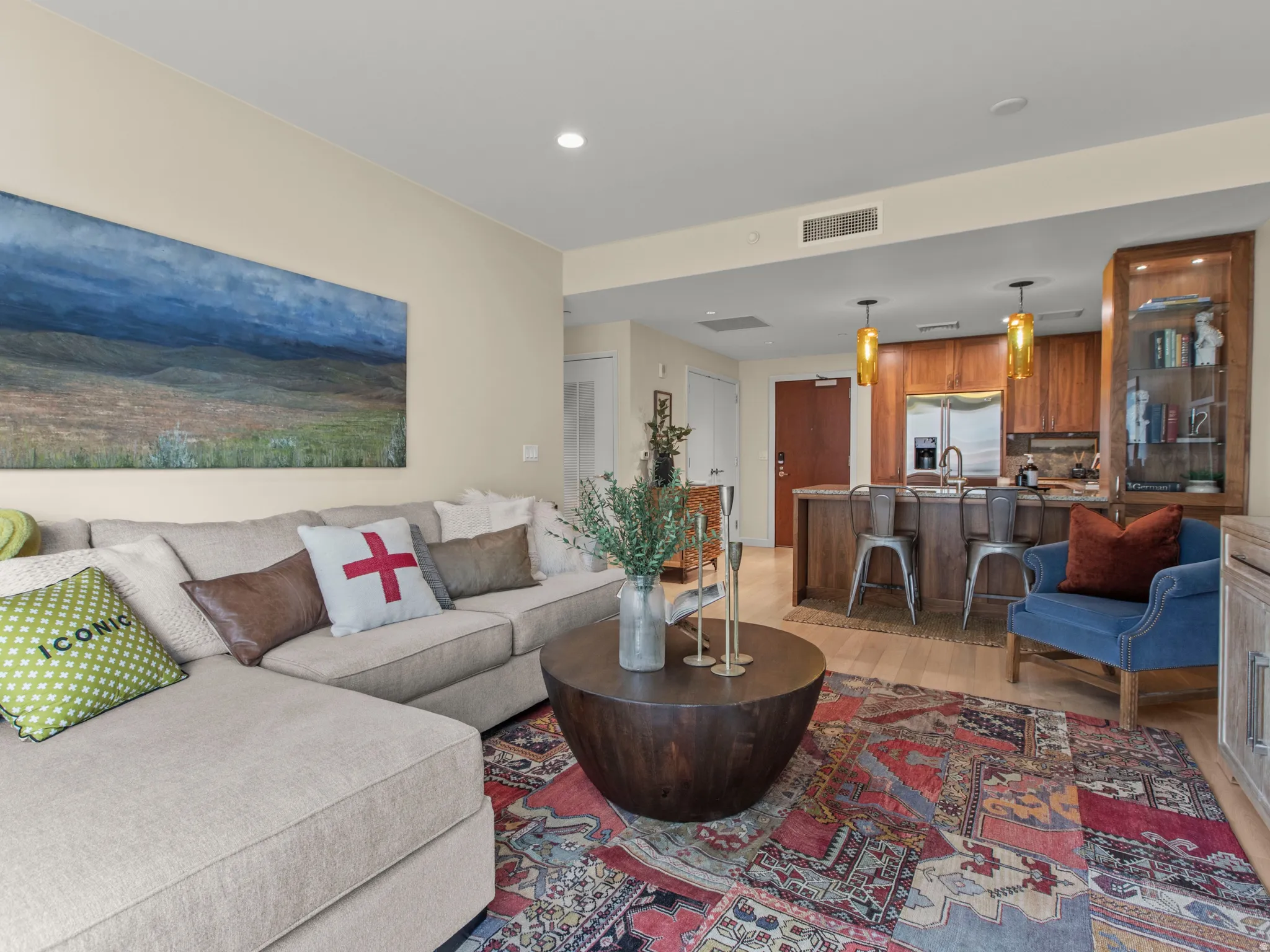 Open-concept living space featuring wood-finish flooring, recessed lighting, and a kitchen with stainless steel appliances, a breakfast bar, and pendant lighting