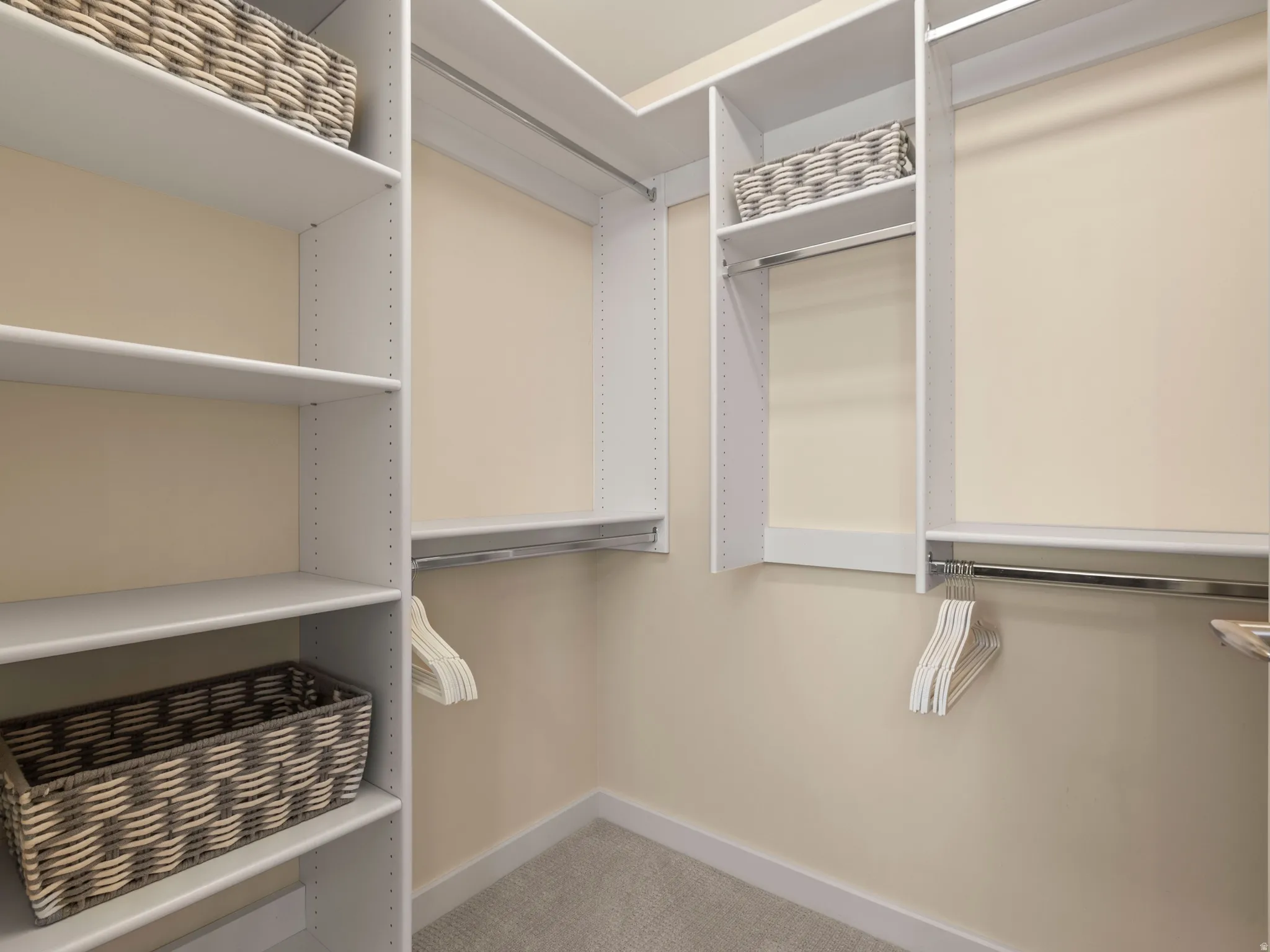 Built-in shelving with adjustable shelves, multiple chrome hanging rods, and carpet flooring