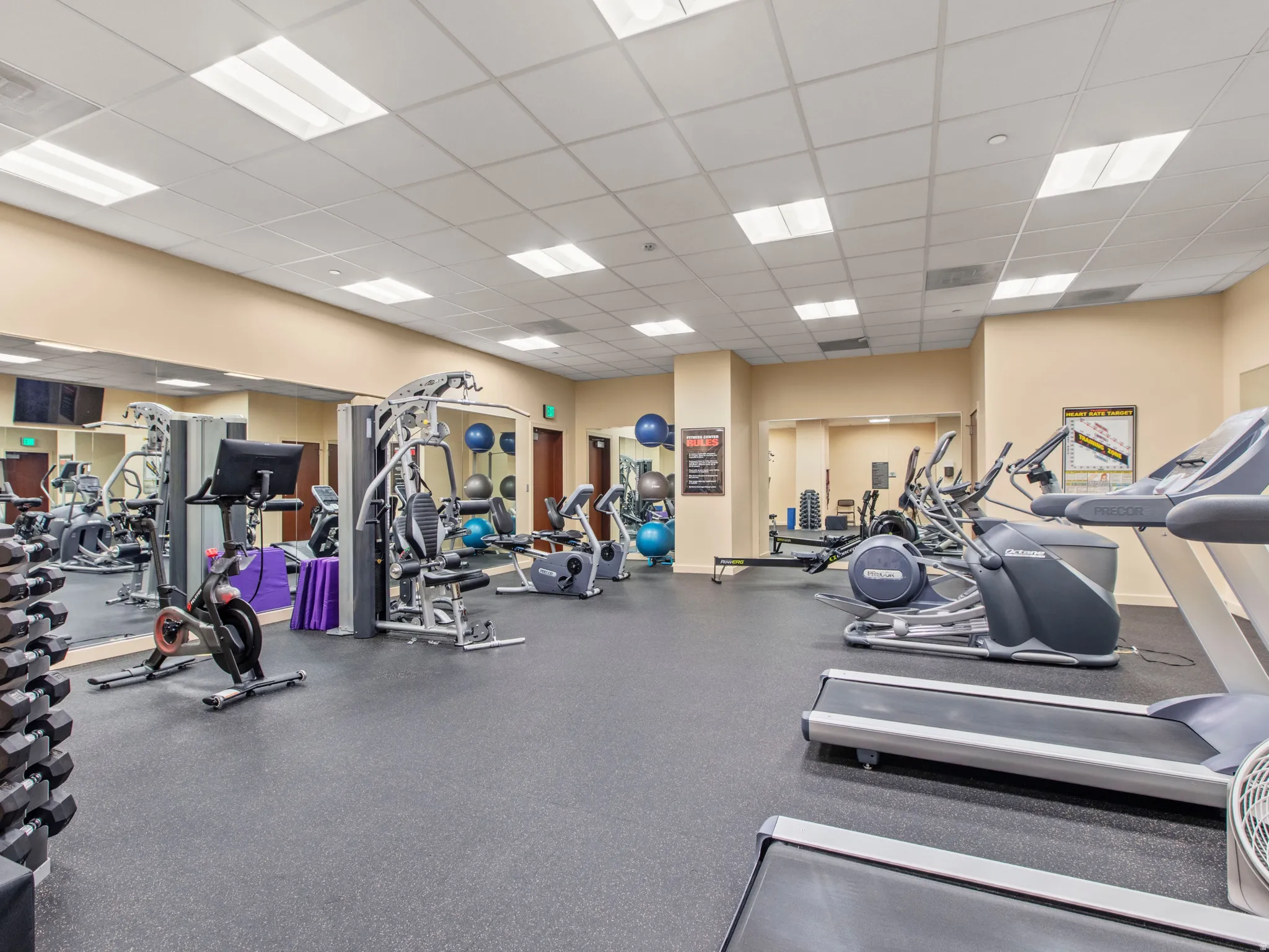 Fitness center featuring rubber-finish flooring, mirrored walls, recessed lighting, and various exercise equipment