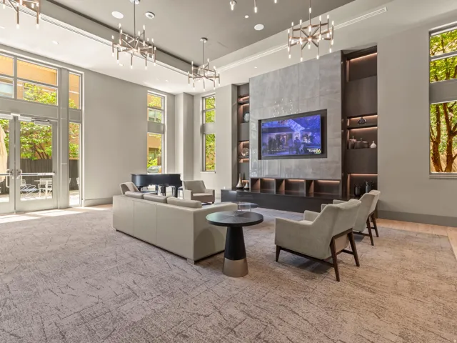 Spacious common area featuring large windows, multiple chandeliers, a built-in media console with shelving, and double glass doors