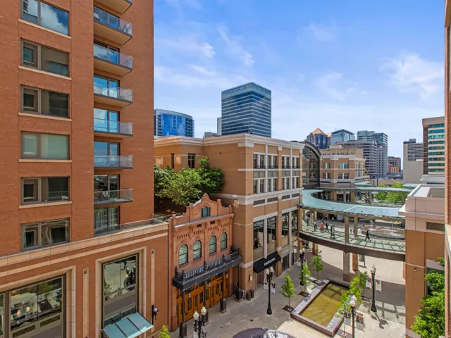 Urban streetscape with brick-clad buildings, commercial storefronts, and a pedestrian skybridge
