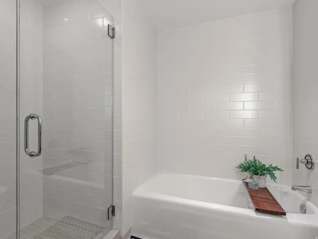 White subway tile surround, glass-enclosed shower, built-in bathtub, and chrome fixtures