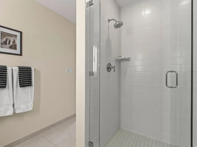 Glass-enclosed shower with subway tile surround, chrome fixtures, and a tiled shower pan