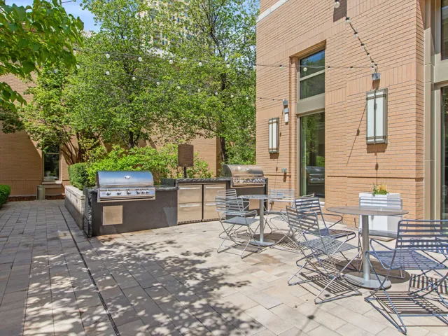 Brick exterior with large windows, paver patio, built-in outdoor kitchen, and integrated grilling stations