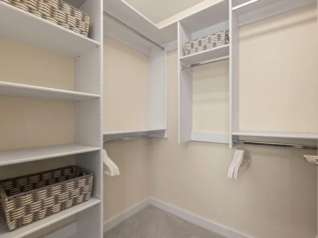 Built-in shelving with adjustable shelves, multiple chrome hanging rods, and carpet flooring