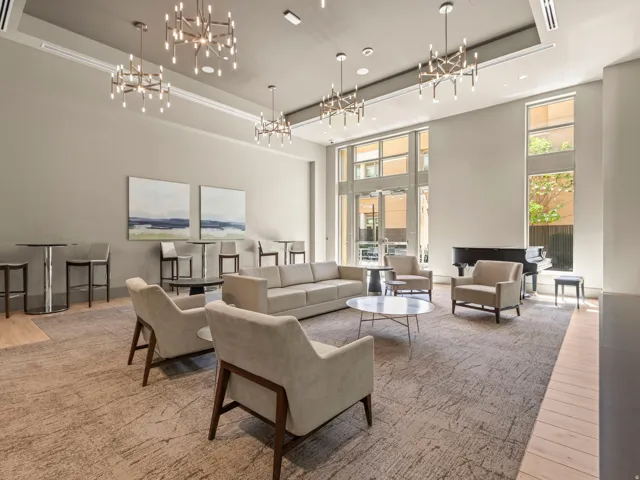 High ceilings with multiple contemporary chandeliers, expansive windows, light wood-finish flooring, and a grand piano