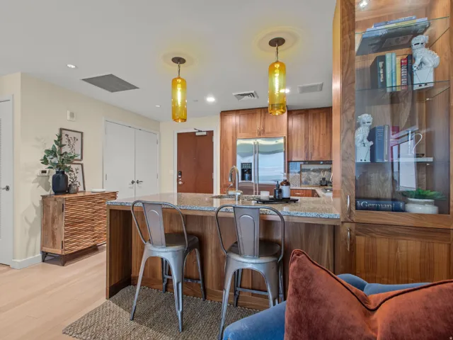 Kitchen island with granite countertop, wood-finish cabinetry, stainless steel appliances, and integrated display shelving
