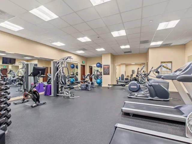 Fitness center featuring rubber-finish flooring, mirrored walls, recessed lighting, and various exercise equipment